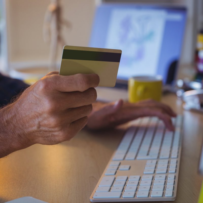 Cropped businessman shopping online with credit card at office